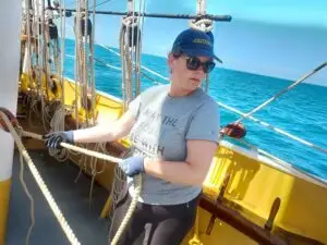 Guest crew member handling a line under blue skies on Morgenster