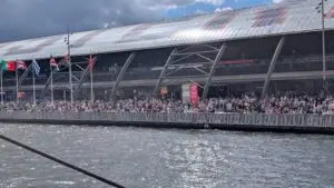 Crowds at Amsterdam Central Station waving at passing tall ships